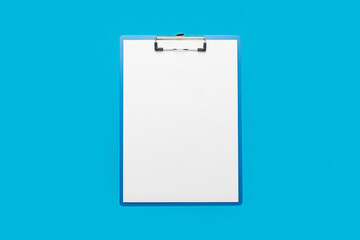 Clipboard with a blank sheet on a blue background. Concept questionnaire, form, contract. Banner. Flat lay, top view