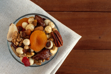 Assorted nuts and dried fruits in bowl on linen fabrics. Top view, space for text