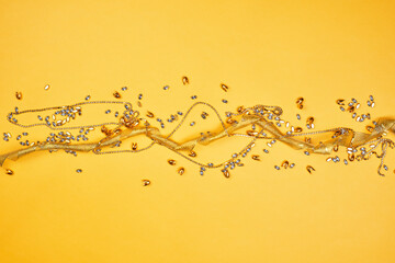 Golden jewelry items and ribbon on the yellow background with copy space