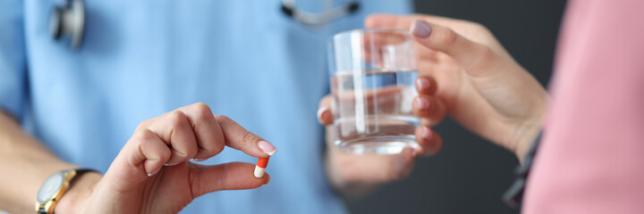 Doctor hands the patient pill and glass of water. Medication overdose symptoms and emergency care concept
