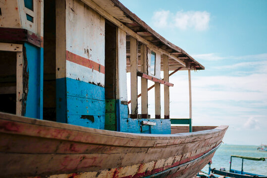 Brown and blue wooden boats are on land for repair. The sky was a clear blue