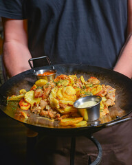 Fried potatoes in an iron pan served in a restaurant or diner. Waiter service, eating out concept.