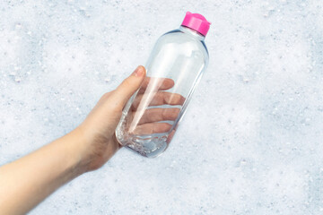 Bottles of detergents float in the foam. The concept of the dangers of household chemicals. Sodium...