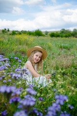 Obraz na płótnie Canvas little girl in a straw hat in a purple field in summer