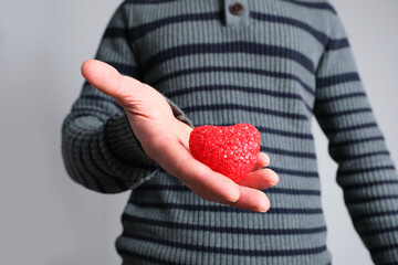 young guy in jacket holding a red heart model in his hand, a symbol of love, concept of confession,...