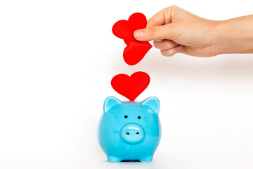 Hand putting many red heart into piggy-bank. Getting tons of likes in social networks. Concept of investing in relationship.