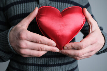 young guy in jacket holding a red heart model in his hand, a symbol of love, concept of confession,...