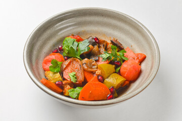 Baked vegetable salad in a cermaic bowl over white background. Delicious healthy autumn or winter salad.