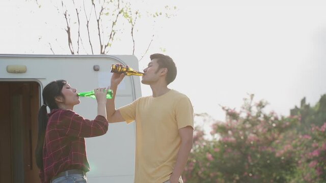 Young asian couple clinking and drinking beer together with happiness.