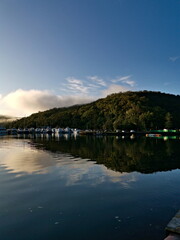 Beautiful morning  view of Cowan creek with reflections of blue sky, mountains, trees and boats, Bobbin Head, Ku-ring-gai Chase National Park, Sydney, New South Wales, Australia
