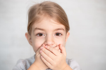 portrait of little girl, child closing his mouth with hands. Speech therapist, speech problems,...