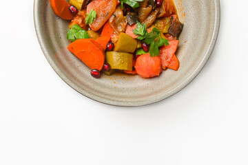Baked vegetable salad in a cermaic bowl over white background. Delicious healthy autumn or winter salad.