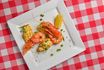 Fresh organic shrimp cocktail with mayonnaise salad. Served on a white plate over red plaid tablecloth.