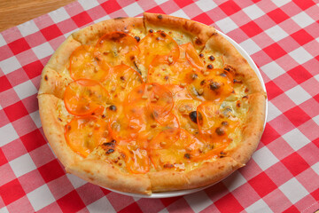 Pizza with persimmon. Italian cuisine concept flat lay, top view. Persimmon dishes menu over red plaid tablecloth.