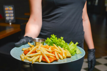 Roasted chicken meat and french fries served by waiter in restaurant or diner, idea for a full meal for dinner.