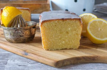 Lemon cake on wooden board with citrus press and halved fresh lemons