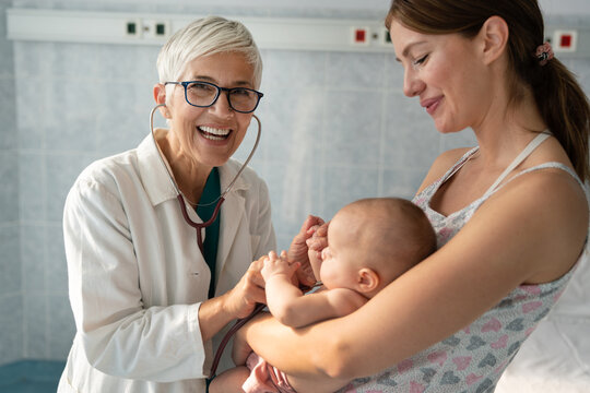 Happy pediatrician doctor with baby checking possible heart defect