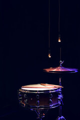 Fototapeta na wymiar Snare drum and hi-hat in the dark on a blurred background with lights copy space.
