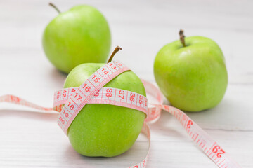 Measuring tape wrapped around green apple on white background, Concept of the goal to lose weight,the goal of diet,