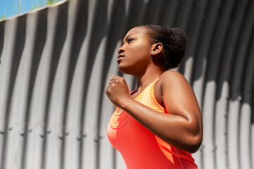 fitness, sport and healthy lifestyle concept - young african american woman running in tunnel