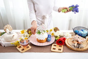 Obraz na płótnie Canvas The process of decorating with flowers a festive Easter table with treats.