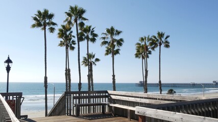 Wooden stairs, beach access in Oceanside, California USA. Coastal stairway, pacific ocean waves and palm trees. Vacations by sea in United States. Sunny tropical day, summertime aesthetic. Staircase.