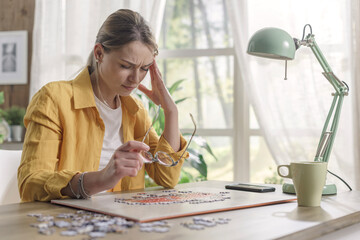 Woman solving a puzzle and having a headache