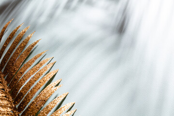 Gold palm leaves and shadows on a blue wall background.