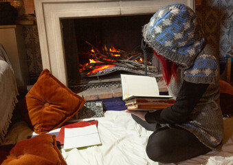 Mujer delante de la chimenea sentada en el suelo,  trabajando y estudiando en el hogar 