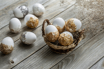 Easter composition with decorated eggs in a basket on a wooden surface.