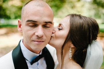 The bride and groom kissing in the park.