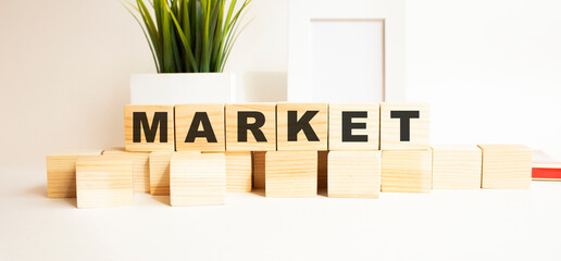 Wooden cubes with letters on a white table. The word is MARKET. White background.
