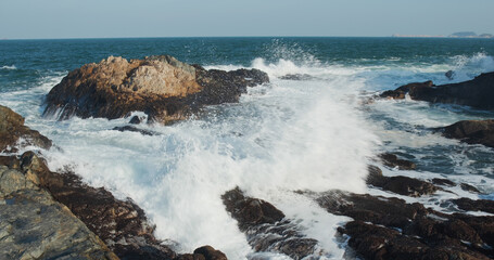 Sea waves splash against rock on island