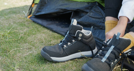 Woman tying her shoes after hiking at camping site