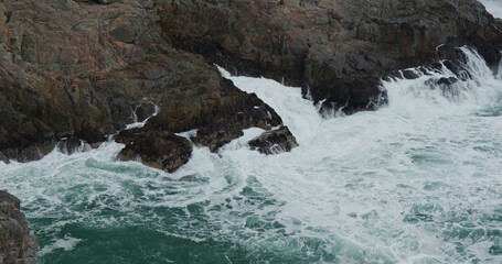 Ocean waves splash against rock on island