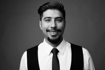 Young bearded Iranian businessman against gray background