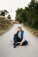 Portrait Of A Teen Boy sitting on his skateboard in a path
