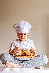 Photo shoot baby in white chef cap with pancakes on white background . Carnival Festival