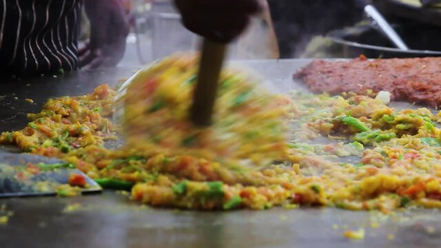 Closeup shot of famous Indian fast food dish Pav Bhaji, a curry made by mashing onions potatoes tomatoes peas capsicum in spices, masala on hot pan. Juhu Beach, Mumbai, Maharashtra, India. 5182.