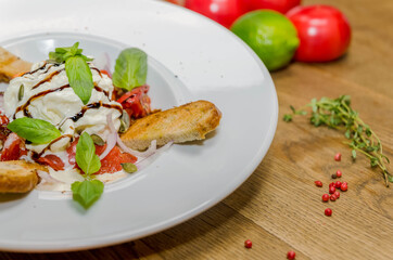 Soft cheese, baguette with tomatoes on a white plate. Close-up