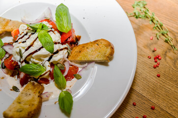 Soft cheese, baguette with tomatoes on a white plate.