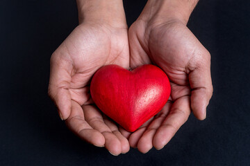Close up on hands holding a red heart 