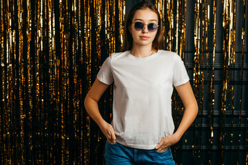 Fototapeta premium Stylish girl wearing white t-shirt and sunglasses posing in studio