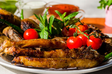 Fresh, homemade grilled beef skewers with vegetables and spices, with barbecue sauce and ketchup, on a white plate close-up