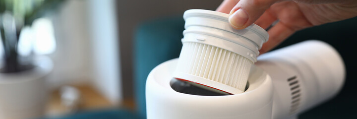 Female hand pull out white filter from white vacuum cleaner close up. Replacement of part in equipment.