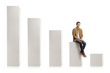 Young casual man sitting on a column from a chart and smiling