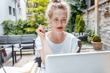 Fototapeta premium Smiling senior woman sitting in coffee shop using laptop.