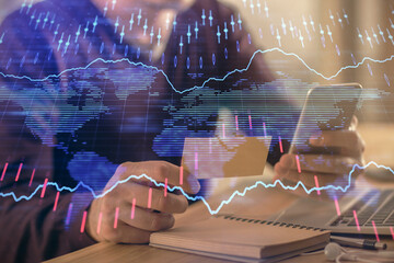 Double exposure of man's hands holding and using a phone and financial graph drawing. Analysis concept.