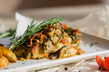 Country style potatoes and stewed chicken breast in mushroom sauce on a rectangular white plate.