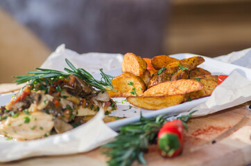 Chicken breast with mushroom sauce and French fries on a plate on the table.